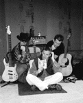 A black && white pic of three Poets -- confused by a guitar manual